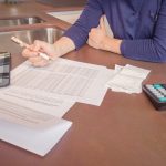 Person reviewing documents with calculator nearby.