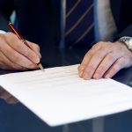 Man signing a document with a pen.