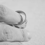 Hand removing a silver ring, close-up.