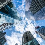 Skyscrapers viewed from below with cloudy sky.