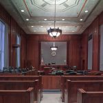 Empty courtroom with wooden benches and podium.