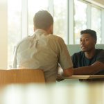 Two people having a conversation at table.