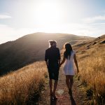 Couple walking on a sunny mountain trail.