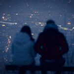 Silhouetted couple overlooking city lights at night.