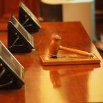 Gavel on wooden table with screens.
