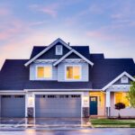 Modern suburban house at sunset with lights.