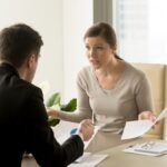 Two people discussing documents at desk.