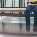Child sitting on a bench, legs dangling.